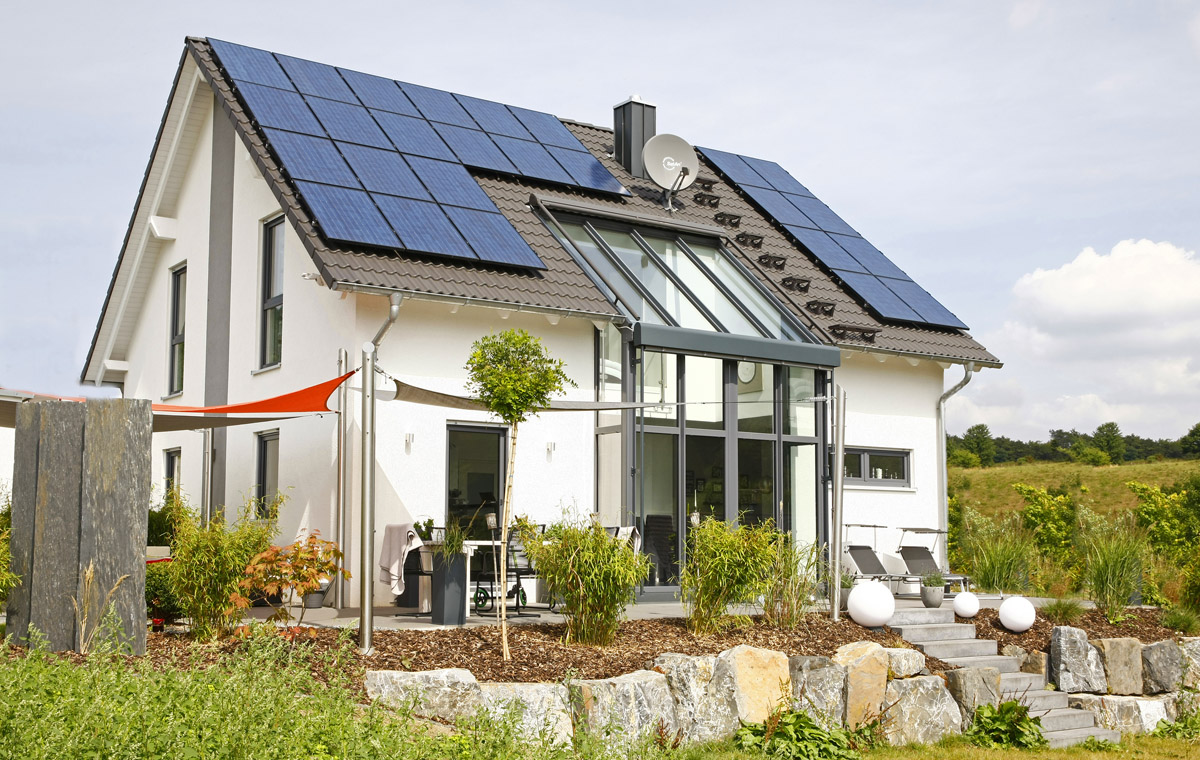 Partner-Haus Fertighaus mit großer Glasfront und Photovoltaikanlage – modernes Referenzhaus mit Garten und Natursteinmauer