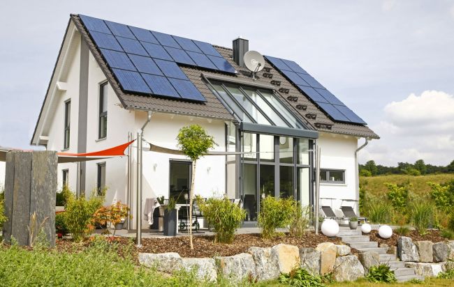 Partner-Haus Fertighaus mit großer Glasfront und Photovoltaikanlage – modernes Referenzhaus mit Garten und Natursteinmauer